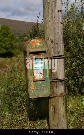 Alter rostgrüner Briefkasten auf einem Holzpfosten auf dem Land Stockfoto