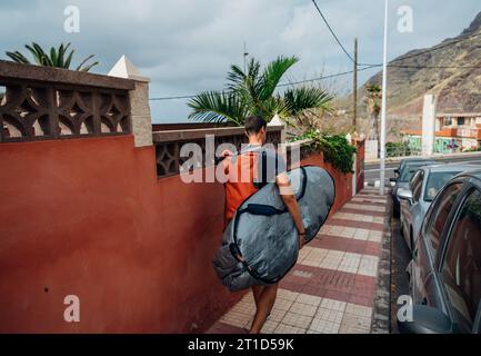 Ein Mann mit einem Surfbrett unter dem Arm, der Wellen fängt Stockfoto