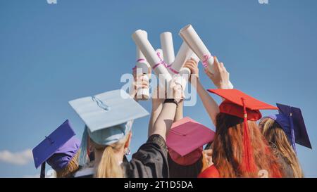 Absolventen heben ihre Diplome zusammen an. Stockfoto