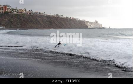 Ein junger Surfer am Strand, der ins Meer springt Stockfoto