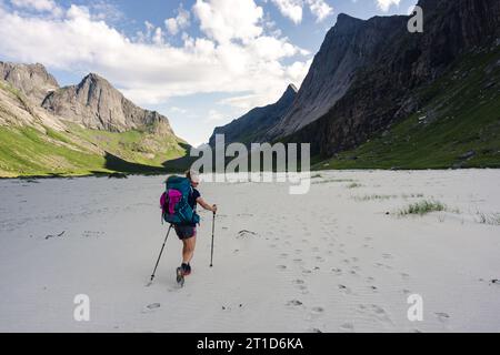 Frau wandert am Strand unter großen Bergen Stockfoto