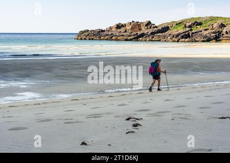 Eine Backpackerin, die am Strand läuft Stockfoto