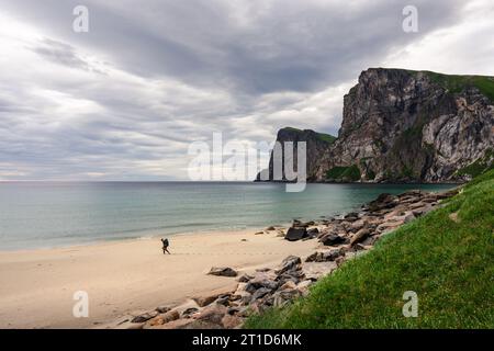 Frau, die am Strand unter großen Klippen entlang läuft Stockfoto