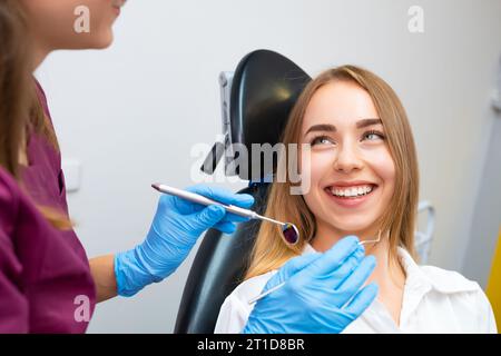 Glückliche Frau im Zahnarztstuhl bereit zur Untersuchung in der Zahnarztpraxis. Stockfoto