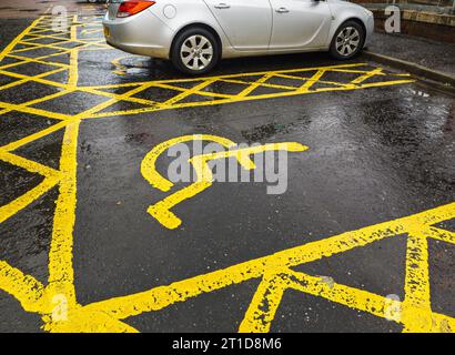Gelbe Straßenmarkierungen auf der Straße zur Kennzeichnung von Parkplätzen mit mehreren Behinderungen in Großbritannien. Parkschild für Behinderte. Behindertenparkplätze, citi für Behinderte Stockfoto