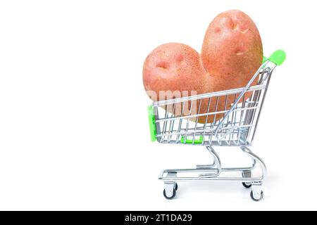 Rohe herzförmige Kartoffel in einem winzigen Einkaufswagen isoliert auf weißem Hintergrund. Konzept für Online-Lebensmittel-Marktplätze. Stockfoto