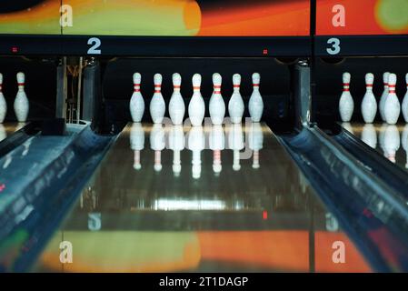 Weiße Bowlingnadeln spiegeln sich in der Bowlingbahn wider Stockfoto