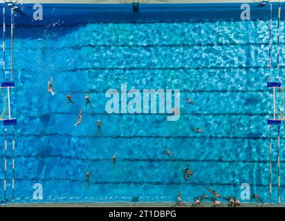 Luftdrohne von oben nach unten Blick auf den Swimmingpool mit Athleten, die Wasserpolo trainieren Stockfoto