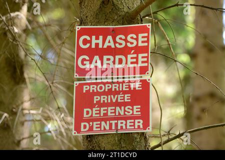 ‚Privat, keine Wilderer‘ und ‚Privateigentum. Kein Betreten“ Schilder auf einem Baum am Eingang zu einem privaten Wald. Stockfoto