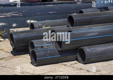 Schwarze Kunststoffleitungen. Ein Haufen von Polyethylenrohren für eine Wasserversorgung. Objekte für die Verlegung von Stadtkommunikation und Kanalisation. Die Konz Stockfoto