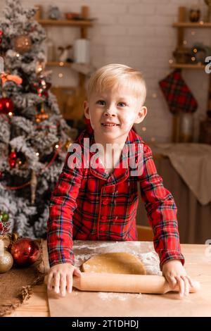 Der Junge im roten karierten Pyjama kocht Weihnachtskekse in der Küche. Kleiner Koch. Hochwertige Fotos Stockfoto