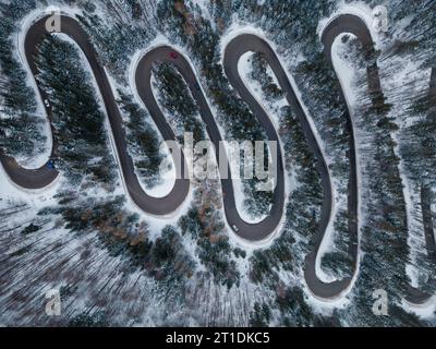 Von oben nach unten auf die winterliche kurvenreiche Straße im dichten Wald, Transsilvanien, Rumänien. Stockfoto