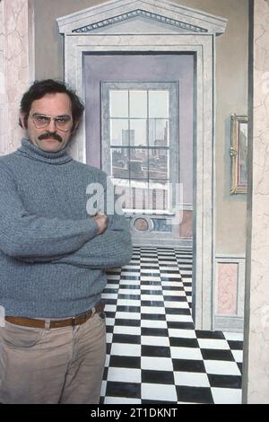Der Trompe-L’Oiel-Künstler Richard Haas steht vor einer seiner Werke. 1977 in seinem Greenwich Village Loft in Soho, New York City. Es ist eine bemalte Lobby zu einem zusätzlichen Zimmer mit Aussicht, die man sehen würde, wenn es wirklich eine Terrasse gibt. Stockfoto