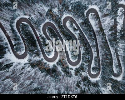 Von oben nach unten auf die winterliche kurvenreiche Straße im dichten Wald, Transsilvanien, Rumänien. Stockfoto