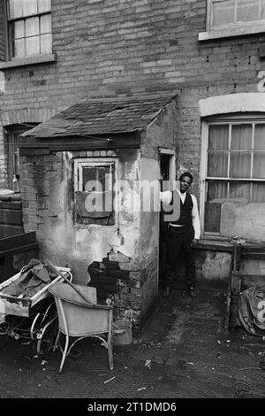 Der schwarze Mann stand während der Räumung und des Abbruchs des Slums in St. Ann's, Nottingham, England, in der Eingangstür seines viktorianischen Reihenhauses. 1969-1972 Stockfoto