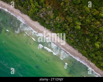 Von oben entfaltete sich der faszinierende Strand mit goldenem Sand, der von türkisfarbenen Wellen gestreichelt wurde. Üppig grüne Wälder schmücken die Küste, während robuste Felsen Stockfoto