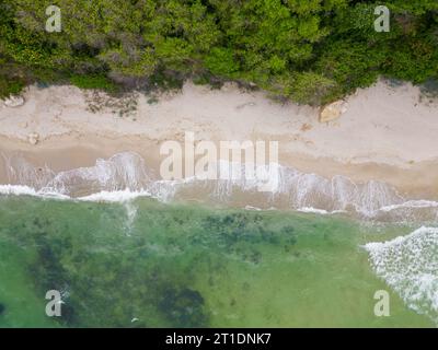 Von oben entfaltete sich der faszinierende Strand mit goldenem Sand, der von türkisfarbenen Wellen gestreichelt wurde. Üppig grüne Wälder schmücken die Küste, während robuste Felsen Stockfoto