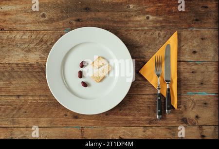 Gericht mit Cracker und roten Bohnen, minimales Konzept für hohe Lebenshaltungskosten, steigende Lebensmittelpreise, hohe Inflation, Armut. Flache Lagen, kostenlose Kopie Spac Stockfoto