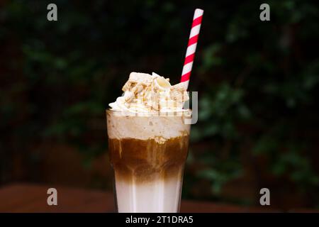 Eiskaffee mit Zimt-Schlagsahne und einem Strohhalm Stockfoto