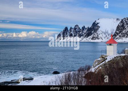 Leuchtturm in der Nähe von Tungeneset mit Teufelszähnen und Ersfjord, Okshornan, Tungeneset, Senja, Troms oder Finnmark, Norwegen Stockfoto