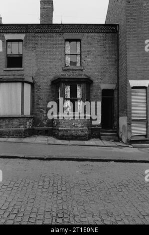 Ein kleiner Junge, der hinter seinen Vorhängen im Vorderzimmer blickt, 21 Crown Street, St Ann's, Nottingham, während der Räumung des Slums und des Abrisses der Gegend 1969-72 Stockfoto