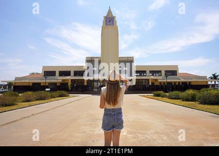 Tourismus in Goiania, Brasilien. Rückansicht einer jungen Touristenfrau, die in Richtung des ehemaligen Art-Deco-Bahnhofs in Goiania, Goias, Brasilien, geht. Stockfoto