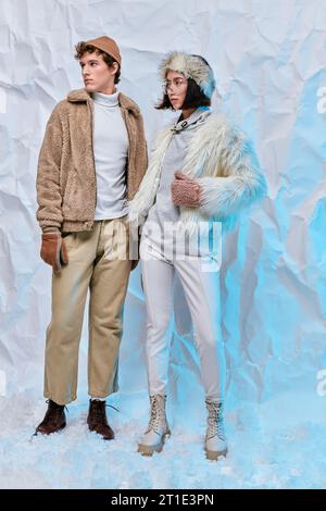 Die ganze Länge interrassischer Models in kaltem Wetter posieren vor weißem, zerknittertem Hintergrund Stockfoto