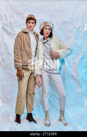 Die ganze Länge interrassischer Models in kaltem Wetter posieren vor weißem, zerknittertem Hintergrund Stockfoto