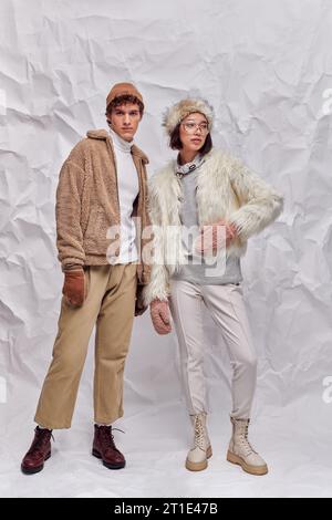 Lange, interrassische Paare in gemütlicher Winterkleidung vor weißem strukturiertem Hintergrund, Wintermode Stockfoto