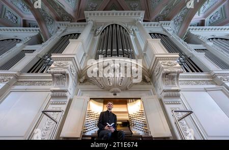 13. Oktober 2023, Sachsen, Leipzig: Markus Kaufmann, Nikolaikantor, sitzt an der Ladegast-Orgel der Nikolaikirche in Leipzig. Im Oktober 2024 jährt sich die Einweihung der renovierten und restaurierten Orgel zum 20. Mal. Der Schwerpunkt liegt seit 2004 auf der Orgelkonsole. In ihren intensiven Bemühungen, das Instrument zu restaurieren, die Pfarrei St. Nikolai erhielt große Unterstützung von Porsche Leipzig. Gemeinsam mit den Orgelbauern der Firma Eule und den Automobildesignern wurde eine Symbiose entwickelt und konzipiert. Das Instrument, das derzeit mit 6822 Rohren und 103 Timbres ausgestattet ist, wird sein Stockfoto