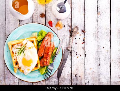 Leckeres Frühstück. Serviert auf einem Holztisch mit Toast, Eiern, Würstchen, Waffeln und Saft. Draufsicht. Stockfoto