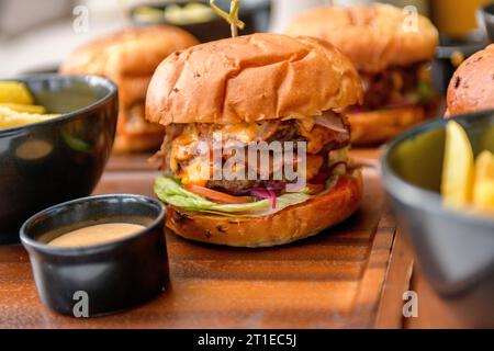 Street Food, Fast Food. Hausgemachte saftige Burger mit Rindfleisch, Käse und karamelisierten Zwiebeln auf dem Holztisch. Stockfoto