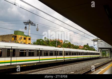 Medellin Metro verlässt eine Station mit Metrokabeln im Hintergrund Stockfoto