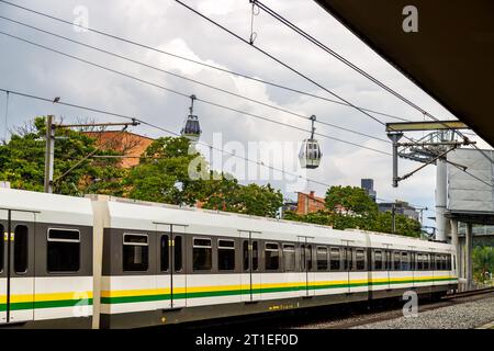 Medellin Metro verlässt eine Station mit Metrokabeln im Hintergrund Stockfoto