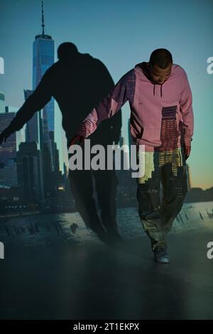 Gut aussehender afroamerikanischer Mann mit Bart in rosa Hoodie, der nach unten blickt, Modekonzept Stockfoto