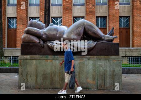 Medellin, Kolumbien - 9. Januar 2023: Man spaziert neben einer Skulptur von Fernando Botero vor dem Museum von Antioquia Stockfoto
