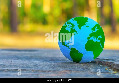 Nahaufnahme einer blauen und grünen Kugel, die auf einem Baumstumpf im Wald platziert wurde. Natur- und Weltharmoniekonzept. Stockfoto