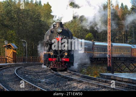 RUSKEALA, RUSSLAND - 06. OKTOBER 2023: Eine alte Dampflokomotive mit einem Personenzug 'Ruskeala Express'. Karelien Stockfoto