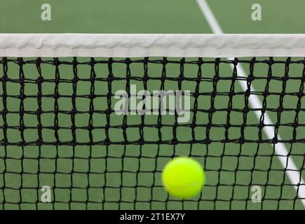 Ein Tennisball in Bewegung nahe der Unterseite des Netzes und des Bildes Stockfoto