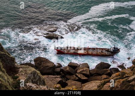 Horizontales Tagesbild mit einem rostigen alten Schiffswrack auf Grund einer Klippe mit rauem Meer, keine Menschen und von oben gesehen Stockfoto