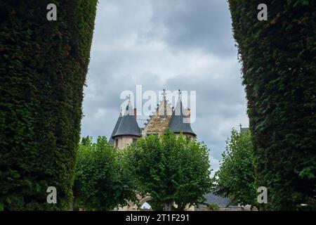 Angers, Frankreich, 2023. Im formellen Garten, die spitzen Dächer des 15. Jahrhunderts. Die Türme des Châtelet sind durch den Bogen eines Eibenkanals zu sehen Stockfoto