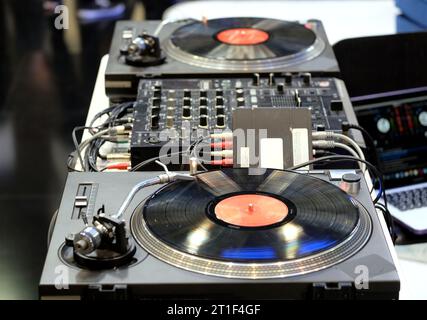 Moderne DJ-Konsole mit zwei Vinyl-Playern mit Platten, Mischpulten und Verbindungsdrähten im Nachtclub aus nächster Nähe Stockfoto