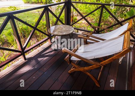 An einem sonnigen Tag stehen zwei leere Holzstühle auf der Terrasse eines Bungalows Stockfoto