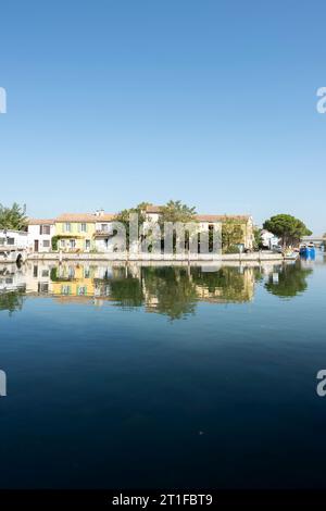 Lebendig bemalte Häuser säumen die Ufer des Rhone-Kanals im malerischen Aigues-Mortes, Occitanie, Frankreich Stockfoto