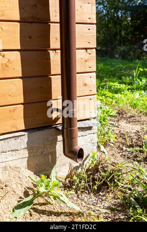 Das neue Regenwasserabflussrohr aus Kunststoff an einem Holzhaus in Nahaufnahme Stockfoto