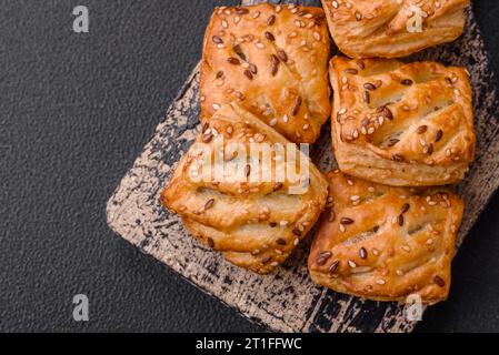 Köstliche knusprige Mini-Puffs mit Wurst oder Fleisch mit Salz, Thymian und Sesam auf dunklem Betonhintergrund Stockfoto