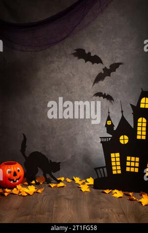 DIY halloween Studio Set Hintergrund mit orangem Kürbiskopf, Fledermäusen, schwarzer Katze Silhouette und einem gespenstischen Haus, grauem Leinwand Hintergrund. Stockfoto