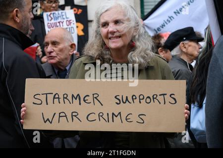 London, Großbritannien. 13. Oktober 2023. Eine Frau hält ein Plakat, auf dem der Vorsitzende der Labour-Partei, Sir Keir Starmer, beschuldigt wird, Kriegsverbrechen während eines Protestes des International Jewish Anti-Zionist Network gegen seine "uneingeschränkte Unterstützung" des israelischen Angriffs auf besänftigtes Gaza nach Angriffen der Hamas auf Israel unterstützt zu haben. Herr Starmer hat sich geweigert, die israelische Drohung zu verurteilen, die zwei Millionen Menschen in Gaza von Nahrungsmitteln, Wasser und Elektrizität abzustellen, während die Demonstranten einen sofortigen Waffenstillstand forderten. Quelle: Ron Fassbender/Alamy Live News Stockfoto