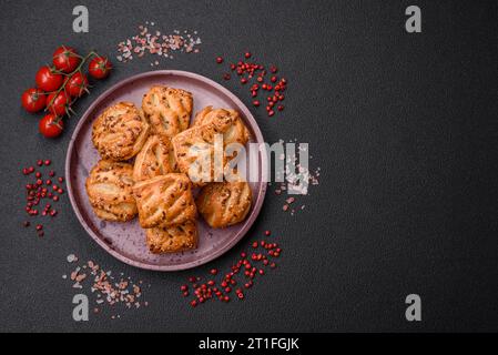 Köstliche knusprige Mini-Puffs mit Wurst oder Fleisch mit Salz, Thymian und Sesam auf dunklem Betonhintergrund Stockfoto