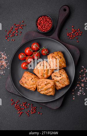 Köstliche knusprige Mini-Puffs mit Wurst oder Fleisch mit Salz, Thymian und Sesam auf dunklem Betonhintergrund Stockfoto